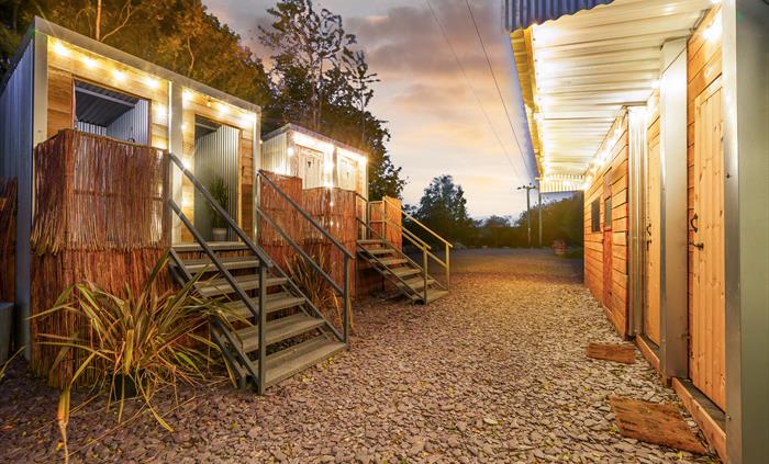 Rustic stylish compost toilets and eco washing facilities, festoon lights in twilight